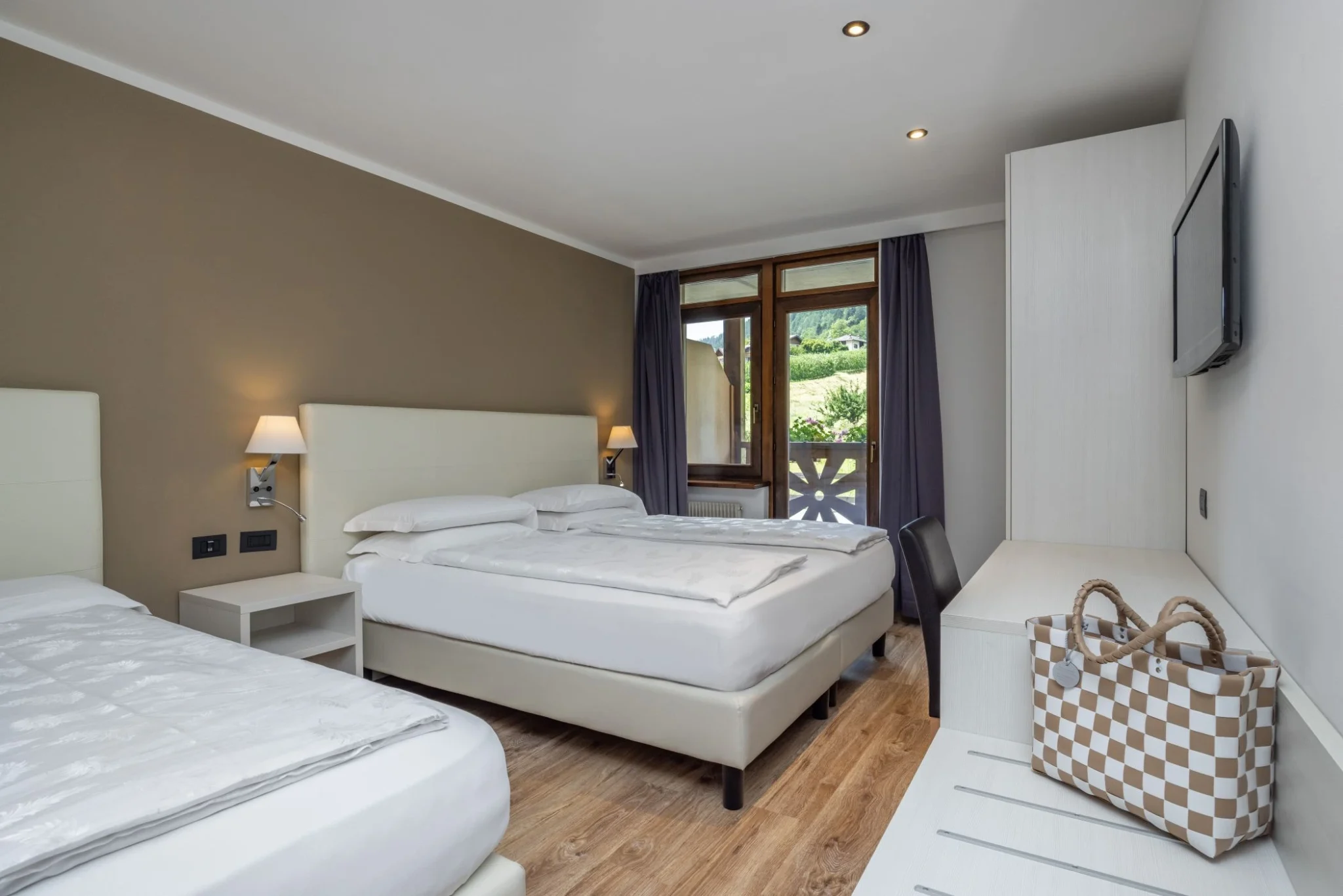 Camera tripla family classic con arredamento dalle linee pulite e vista dalla finestra